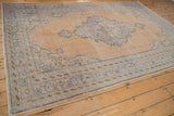 Worn texture and time-softened tones on the Oushak rug border with blue and sand motifs.