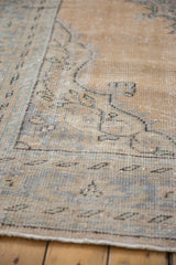 Distressed texture of vintage Oushak rug pile with faded beige, sand, and blue motifs.