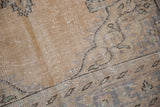 Abrashed softened pile of vintage Oushak rug, displaying muted sand, faded blue, and charcoal patterns.
