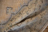 Close-up of distressed Oushak rug pile, featuring faded sand, beige, and soft blue tones.