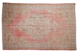 Faded cherry red distressed Oushak rug with ivory Rococo medallion and abrashed field.