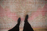 Distressed Oushak carpet displaying its worn texture, faded cherry red, blush, ivory patterns.