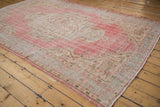 Worn pile of a distressed Oushak rug showing faded blush and seafoam green border.