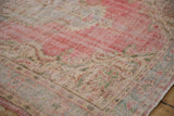 Distressed Oushak carpet showing faded cherry red, ivory outlines, and visible wear.