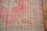 Distressed Oushak rug corner reveals faded red, blush, ivory pile wear, and original side selvage.
