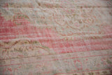 Distressed vintage Oushak rug with wear to foundation, showcasing faded blush, seafoam green, and ivory.