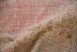 Worn, hand-knotted pile texture of the distressed Oushak rug, with faded red and green.
