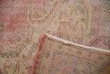 Textured detail of distressed vintage Oushak rug, showing worn blush pile, side cord, and fringe.