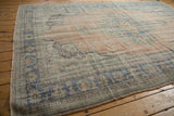 Distressed vintage Oushak rug corner with worn blue, seafoam green border and frayed edge.