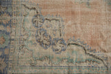 Distressed Oushak carpet corner, dusty rose field, blue green palmette motifs, visible wear.