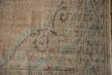 Distressed vintage rug pile with visible knot heads and muted floral design.