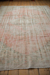 Distressed vintage Oushak carpet texture showing mostly even wear, visible foundation, pink, green, and beige tones.