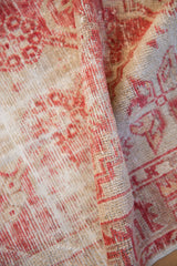 Distressed textured pile with pale cherry red floral motifs on a vintage Oushak runner.