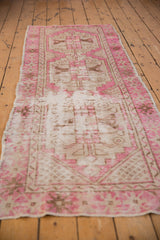 Distressed Oushak runner with fuchsia and ivory geometric medallions, mostly even wear.