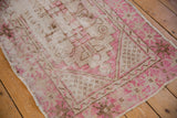 Distressed Oushak runner corner with fuchsia, ivory, brown stepped pattern and exposed foundation.