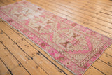 Distressed fuchsia and beige Oushak runner border, showing textured wear and intact side selvage.