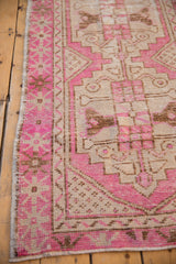 Distressed Oushak runner's fuchsia, beige, and coffee geometric border with intact selvage.