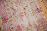 Distressed vintage Oushak runner shows worn fuchsia, ivory pile with visible foundation.