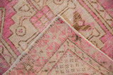 Folded distressed rug corner, fuchsia, ivory, brown stepped geometric patterns, worn pile.