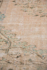 Distressed texture revealing faded beige, seafoam green vinery and floral motifs on Oushak rug.