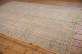 Distressed hand knotted Oushak carpet featuring worn beige pile and soft blue vinery.