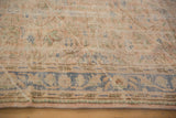 Distressed vintage Oushak carpet showing pale scrolling vinery, border, and distinct diagonal striations.