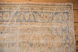 Distressed vintage Oushak rug corner showing worn pile, faded beige, blue, green, with side selvage.