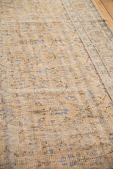 Distressed Oushak carpet texture, faded pale gold, blue, and brown tones, foundation visible.