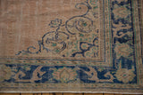 Distressed Oushak rug corner, revealing dusty rose field, cobalt arabesques, and patterned border.