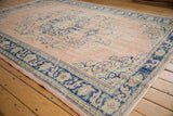 Distressed vintage Oushak rug corner, faded dusty rose field, cobalt blue border design.