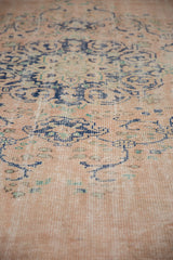Distressed Oushak rug pile with faded dusty rose field, faint foundation, and cobalt blue arabesques.