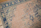 Distressed vintage Oushak pile, dusty rose field with faded blue patterns, faint foundation visible.