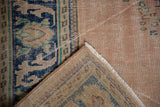 Vintage Distressed Oushak rug corner showing worn dusty rose pile, fringe, and woven foundation.