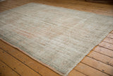 Distressed vintage Oushak rug corner, showing low pile, secure end, and faded pastel hues.