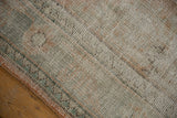 Distressed texture of vintage Oushak carpet, showing worn pile and pale rose-green zig-zag border.