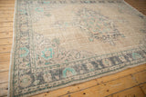 Distressed vintage Oushak rug corner: charcoal and aqua mint border motifs on an ivory field.