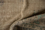 Folded distressed Oushak carpet pile showing worn knot heads, ivory, charcoal and aqua.