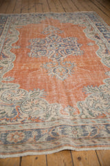 Burnt orange abrashed field with stylized blue vinery and mostly even wear on this Oushak.