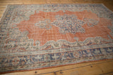 Distressed Oushak carpet corner with decorative serrated leaves, scrolling vinery, rust, and denim blue.