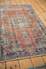 Distressed Oushak rug texture, showing knot heads and foundation in madder red, cobalt blue, and ivory.