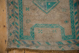 Worn Oushak rug corner, emerald turquoise geometric pattern, exposed foundation.