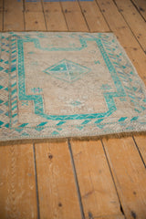 Detail of distressed Oushak rug, showing worn pile texture, intact fringe, and turquoise geometric border.