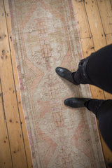 Distressed Oushak rug's muted beige, ivory, pink tones, showing soft floral and diamond patterns.