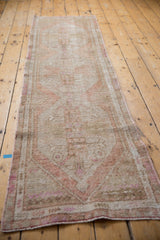 Detail of the distressed texture and softened ivory, beige, and pink tones on the Oushak rug end.