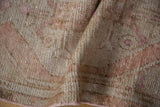 Distressed hand-knotted Oushak rug pile with worn texture and muted ivory-pink colors.