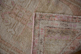Distressed Oushak rug pile shows even wear, visible knot heads, and pink side cord.