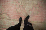 Distressed pink vintage Oushak rug, showing abrashed field and seafoam border wear.