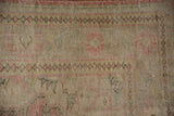 Distressed vintage Oushak rug close-up, worn pile with faded pink, ivory, seafoam patterns.