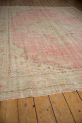 Distressed vintage Oushak rug pile showing wear, with pink and ivory colors and fringe.