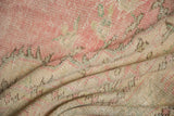 Distressed vintage Oushak rug pile texture showing mostly even wear and soft pink, ivory, pale green.